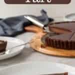 Image with text. Text is dark chocolate tart recipe. slice of chocolate tart with whole tart in the background