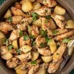 braised chicken wings with potato chunks sprinkled with chopped parsley viewed from above