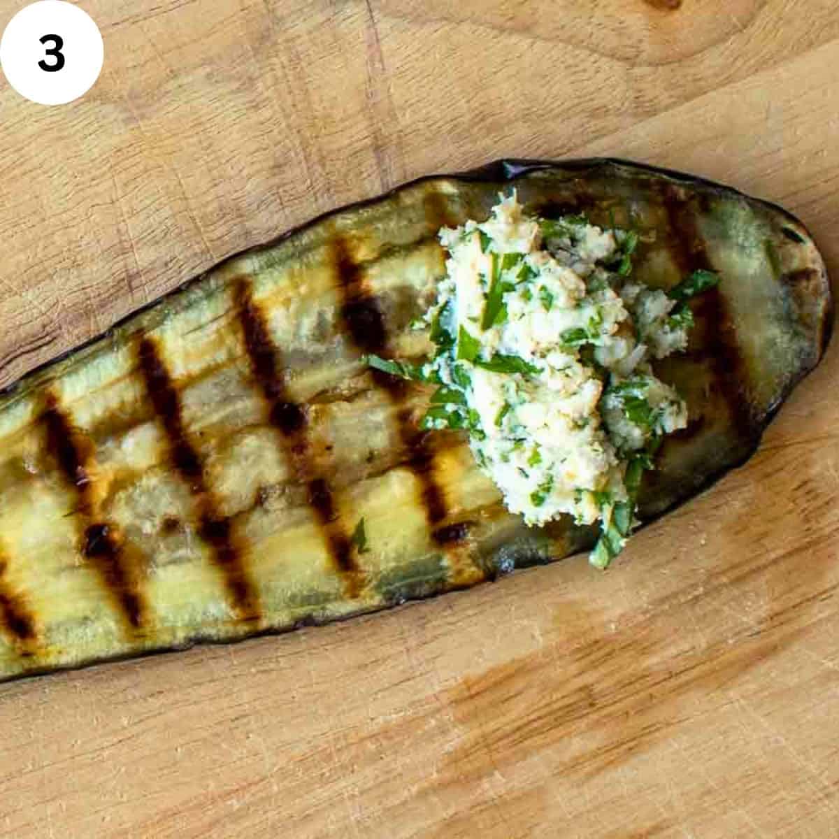 A spoonful of ricotta cheese filling on a grilled slice of eggplant.