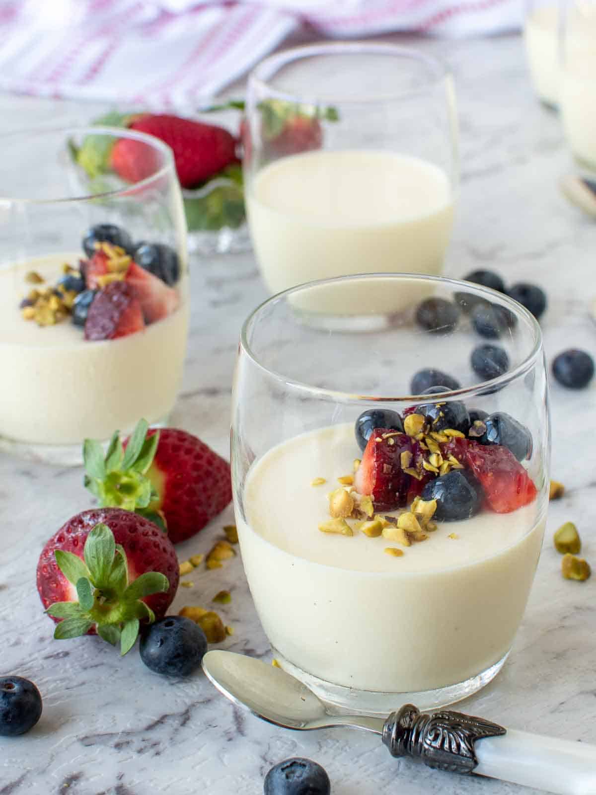 An Italian Panna Cotta Recipe set in glasses with strawberries and blueberries.