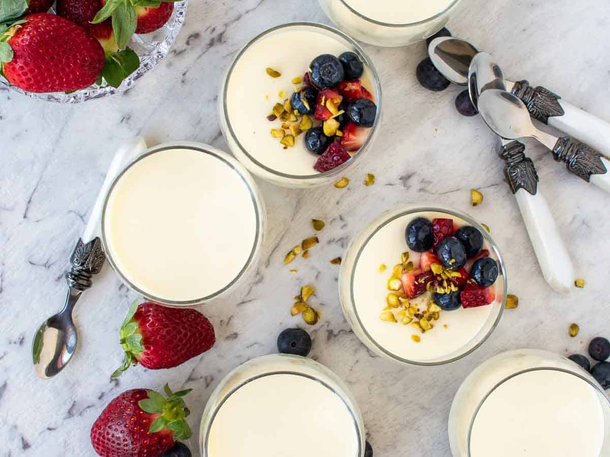 Vanilla panna cotta in glasses with strawberries and blueberries viewed from above.