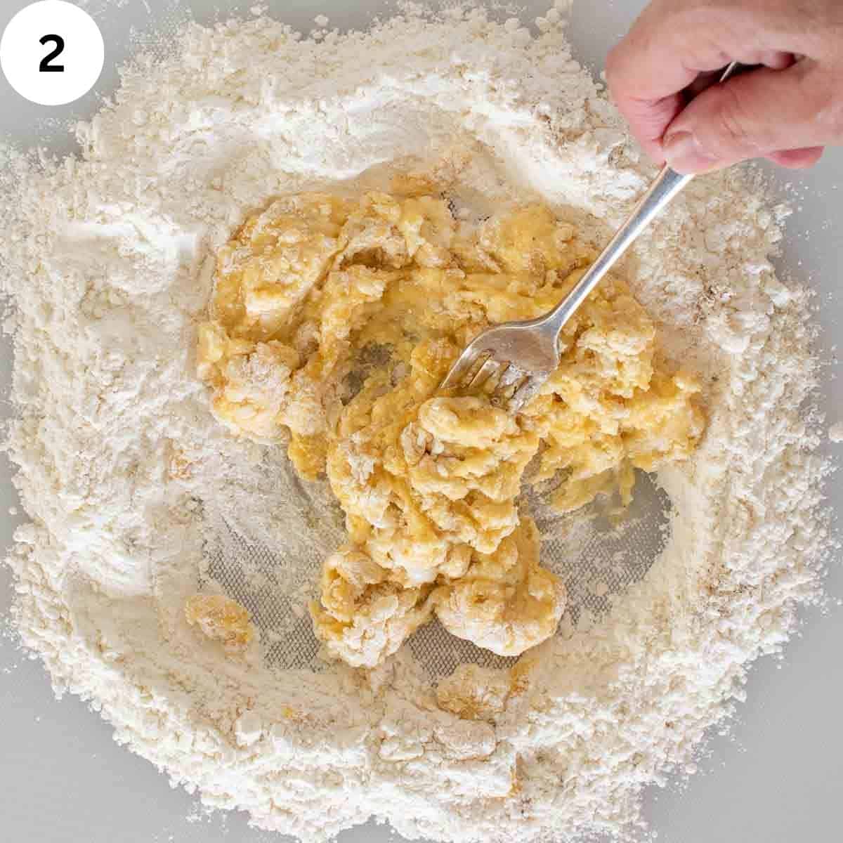 A fork mixing dough with flour around the edges.