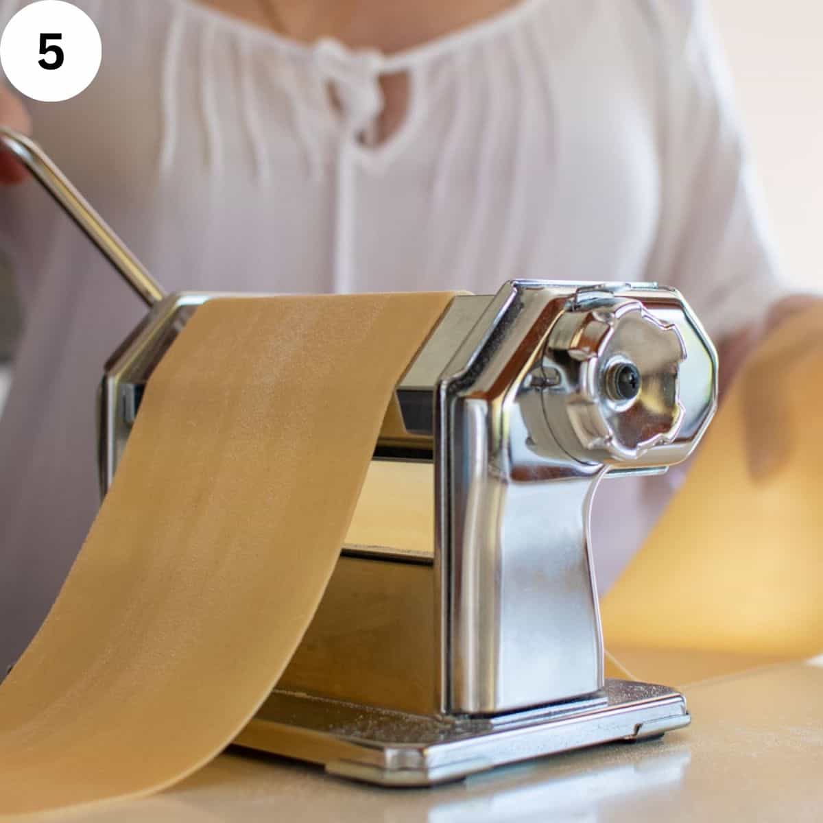 Dough being rolled and stretched using a pasta machine.