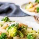 image with text. text reads "broccoli pasta quick and easy". image is broccoli pasta on white plate with second plate of broccoli pasta in the background.