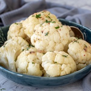 Finished Instant Pot Cauliflower in blue bowl on table viewed from the side.