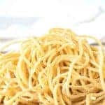 image with text. text reads 'make your own tonnarelli pasta. image is pile of yellow homemade spaghetti on wooden board.