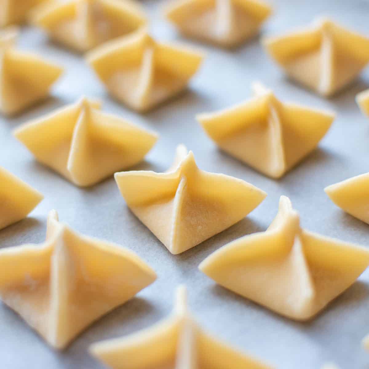 fagottini filled pasta on baking paper viewed side on.