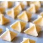 image with text. text reads "cheesy filled pasta handmade fagottini". image is pyramid shaped filled pasta on white baking paper.