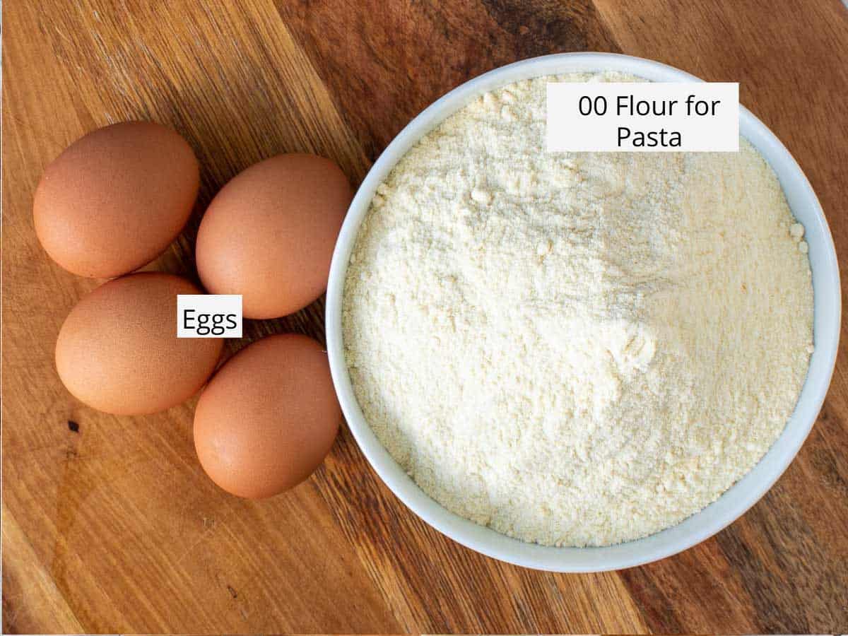 White bowl of flour and four eggs on wooden table viewed from above.