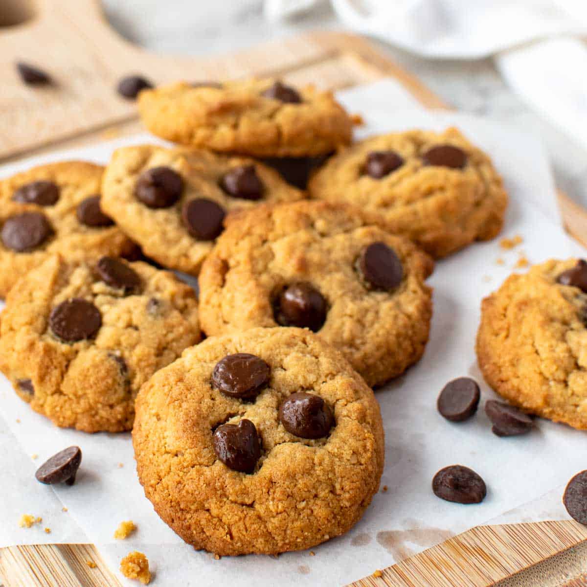 Almond flour peanut butter cookies topped with chocolate chips on white baking sheet.