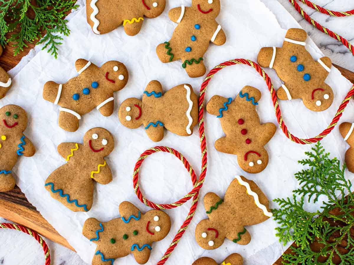 Decorated gingerbread men with red cord and greenery viewed from above.
