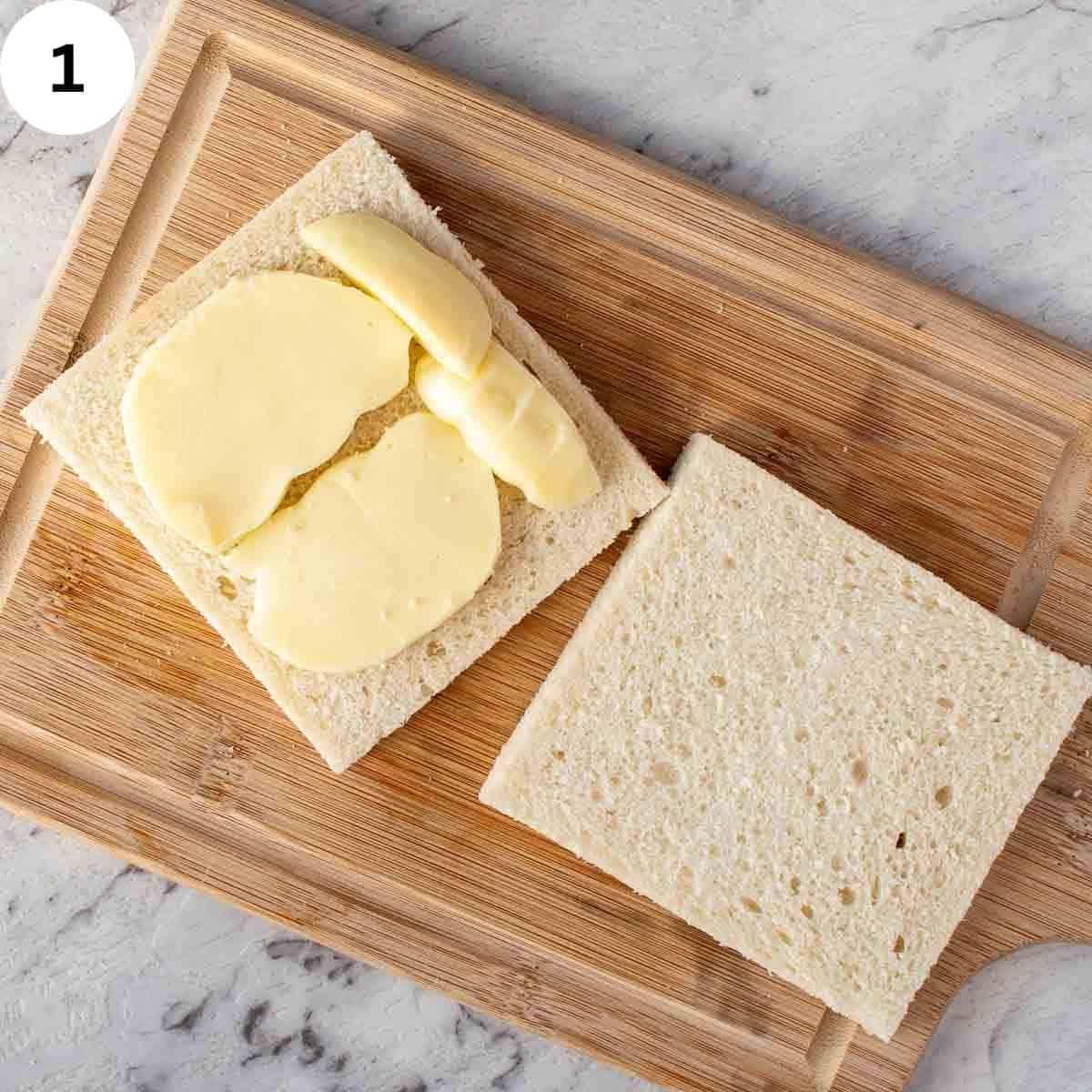 Two slices of crustless white bread, one topped with mozzarella slices.