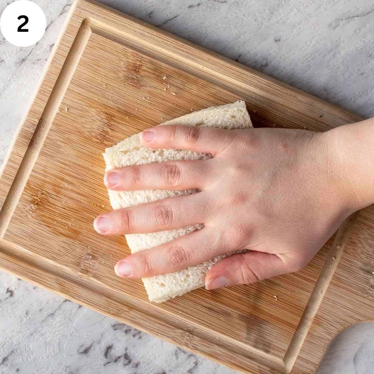 Pressing on a white bread sandwhich with hand.
