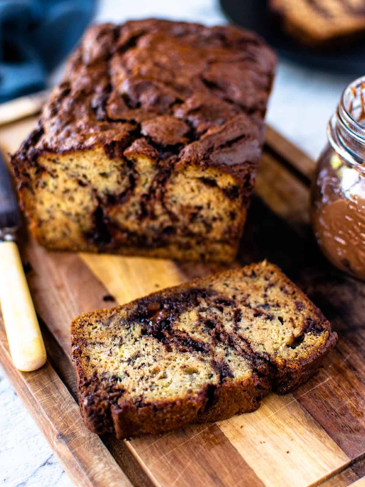 Several slices of baked banana bread with Nutella running through them on a wooden board.