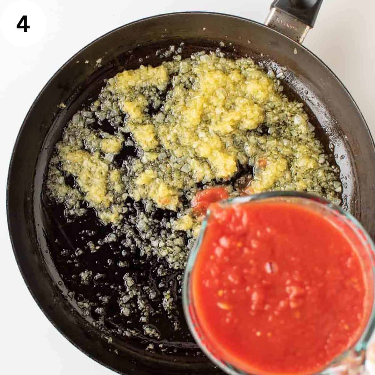Tomato puree being added to cooked, finely chopped onion.