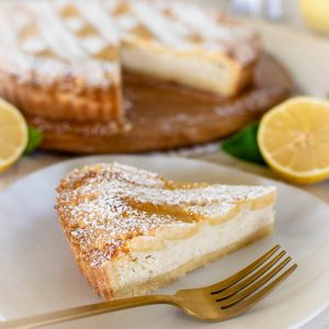 slice of pie on white plate with gold fork and whole pie in the background.