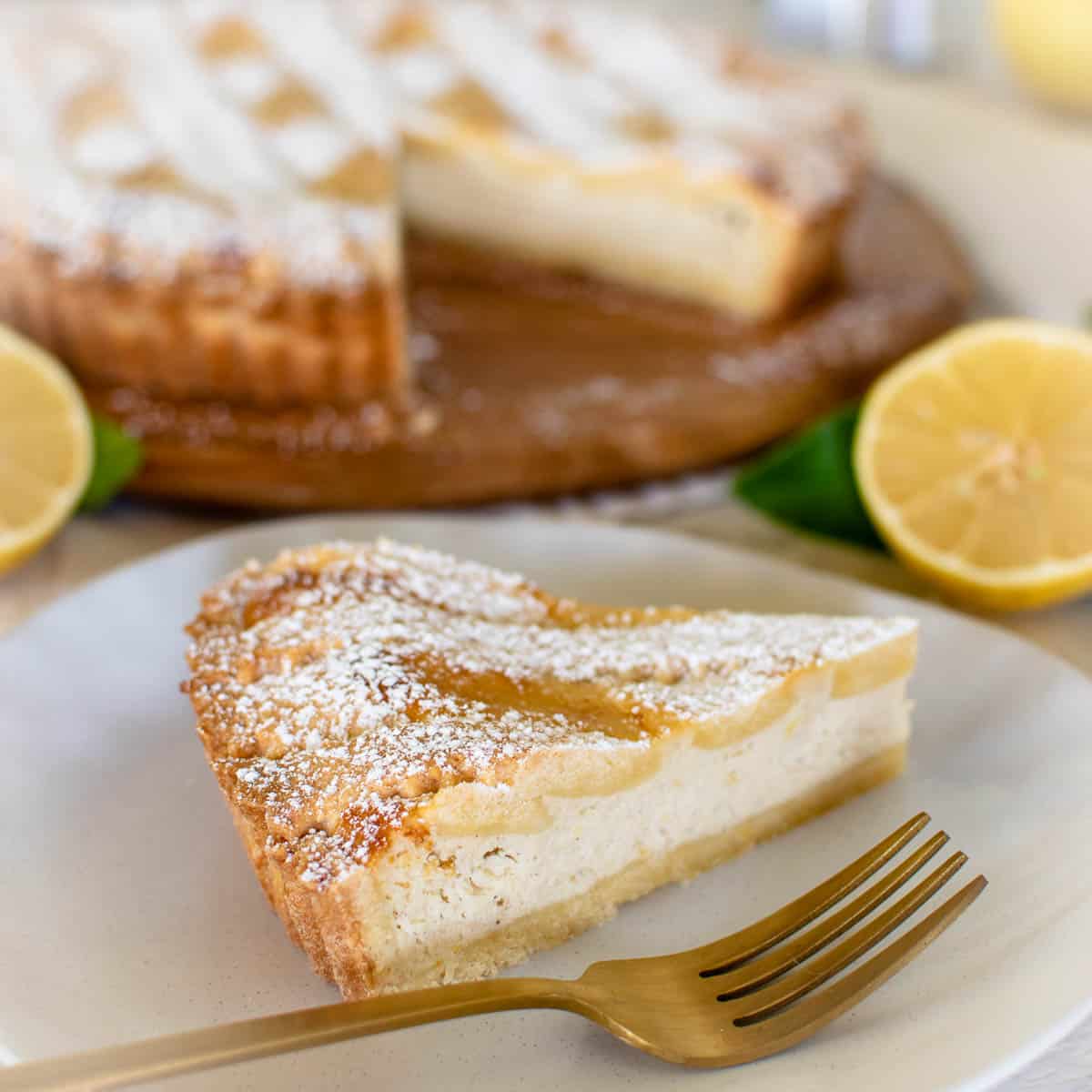 slice of pie on white plate with gold fork and whole pie in the background.