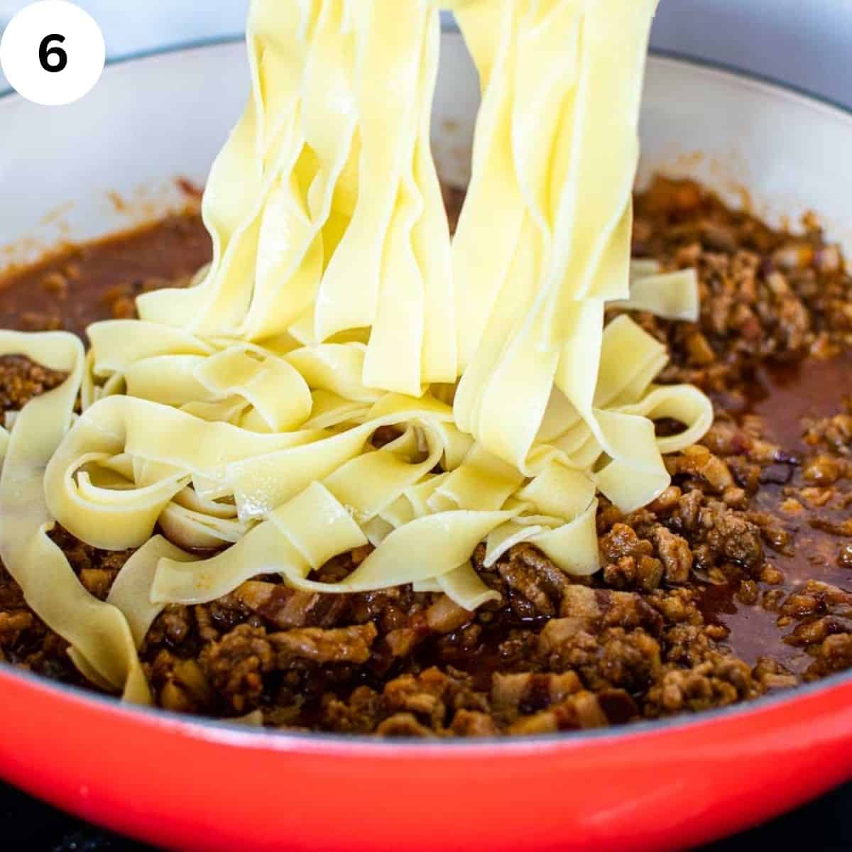 Tagliatelle being added to meat sauce in a round pan.