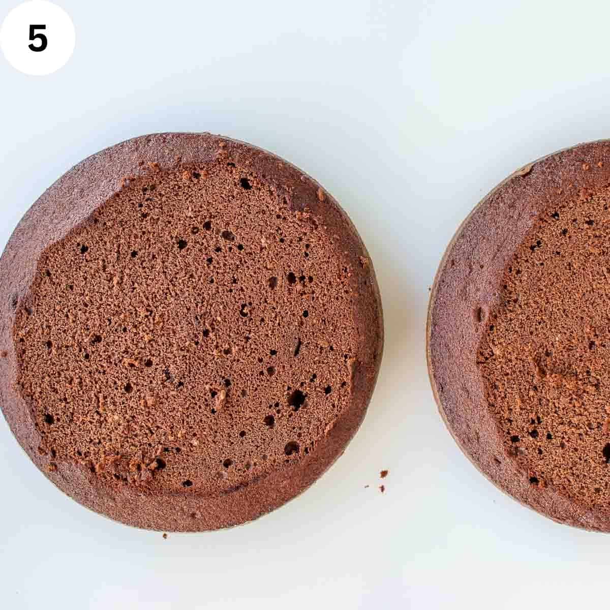Two unfrosted chocolate cakes with tops cut off.