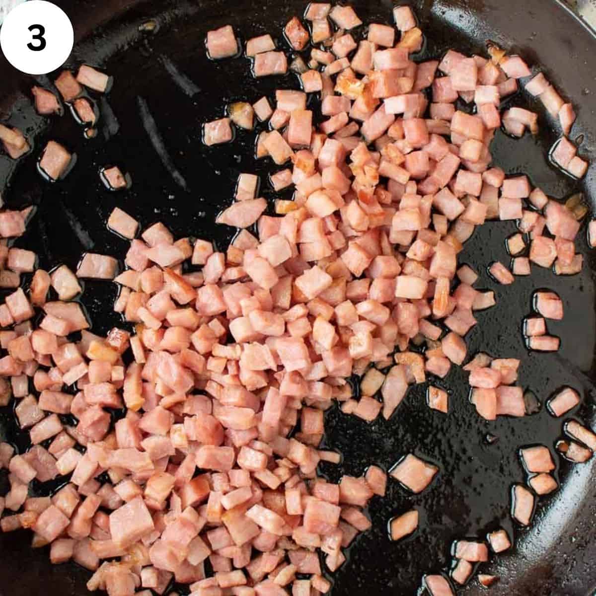 Diced ham sauteeing in a pan.