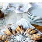 Star shaped pastry with dusting of powdered sugar on white paper.