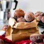 Frittelle coated in sugar in a brown paper bag.