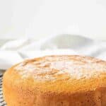 Pan Di Spagna on a black wire rack with granulated sugar on top.