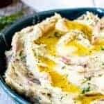 Mashed potatoes with red skin in a blue bowl with melted butter on top.