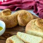 Semolina bread with three slices cut all on wooden board.