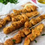 Chicken Spiedini on white baking paper with lemon wedges.