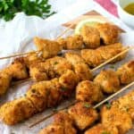 Chicken Spiedini on white baking paper with lemon wedges.