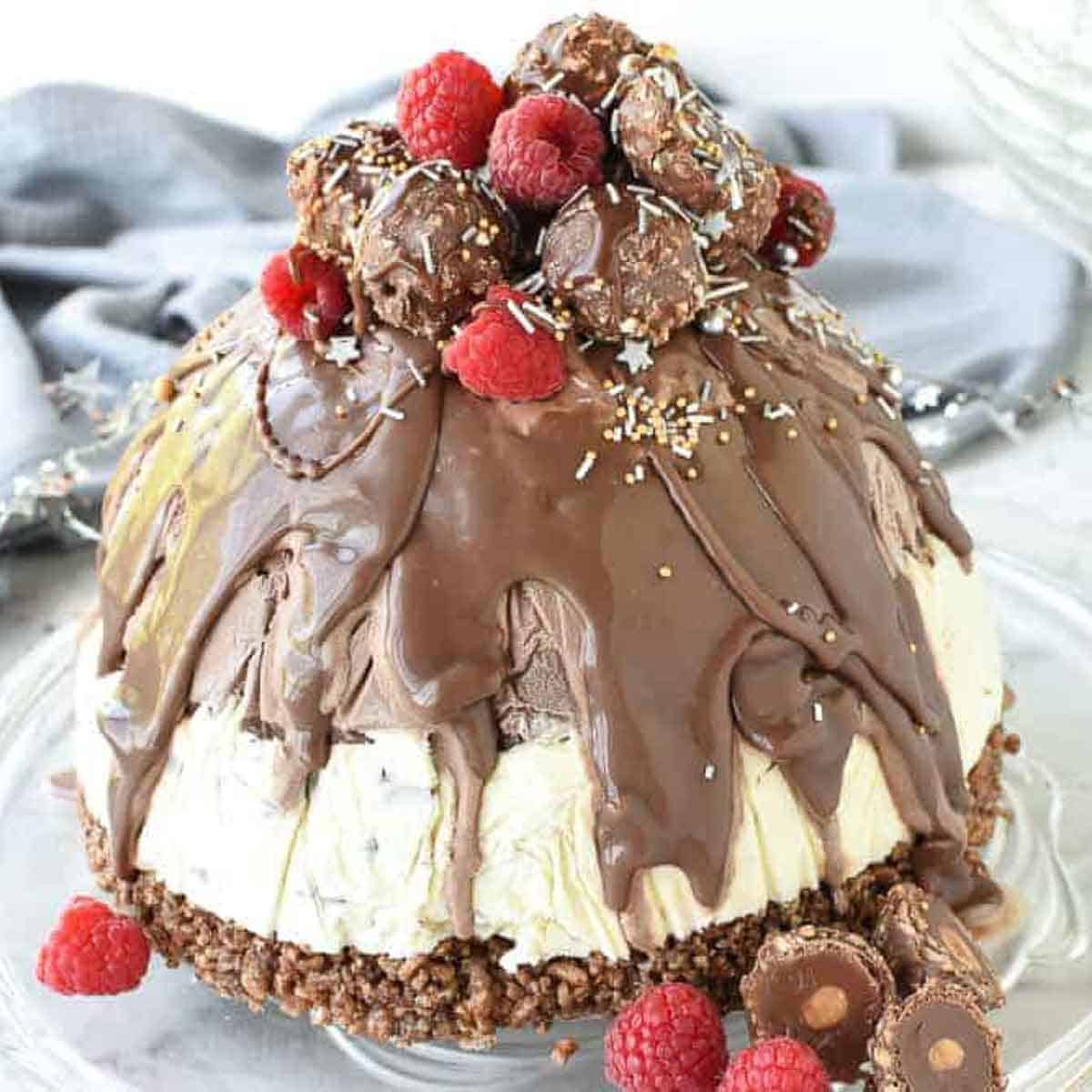 Christmas ice cream pudding with chocolate drip decorated with chocolates and raspberries.