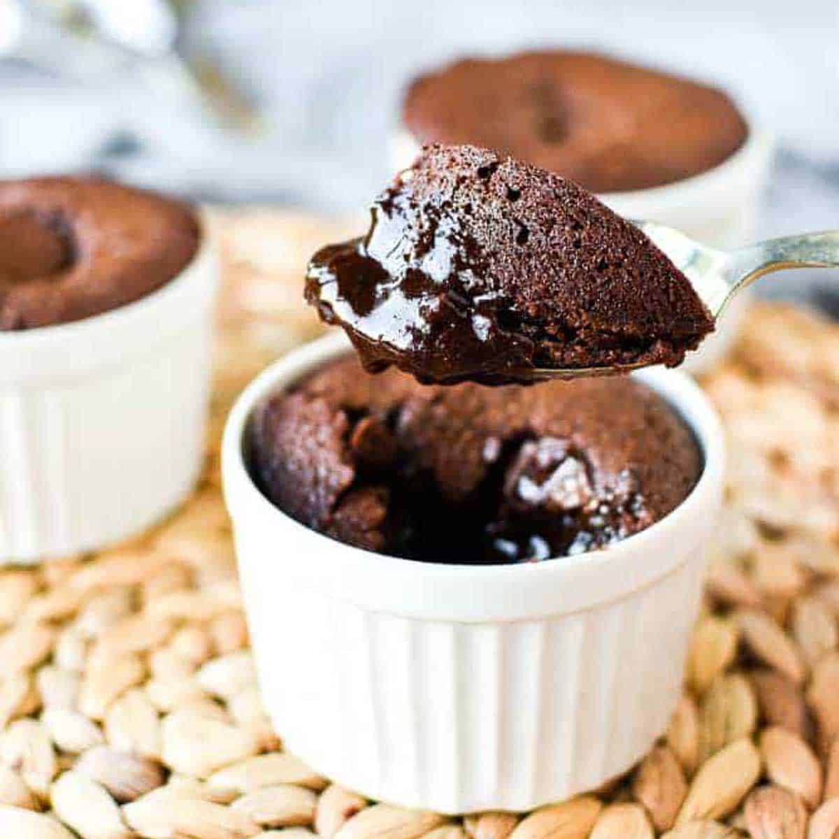 Chocolate pudding in a white pudding cup with a spoonful being lifted out.
