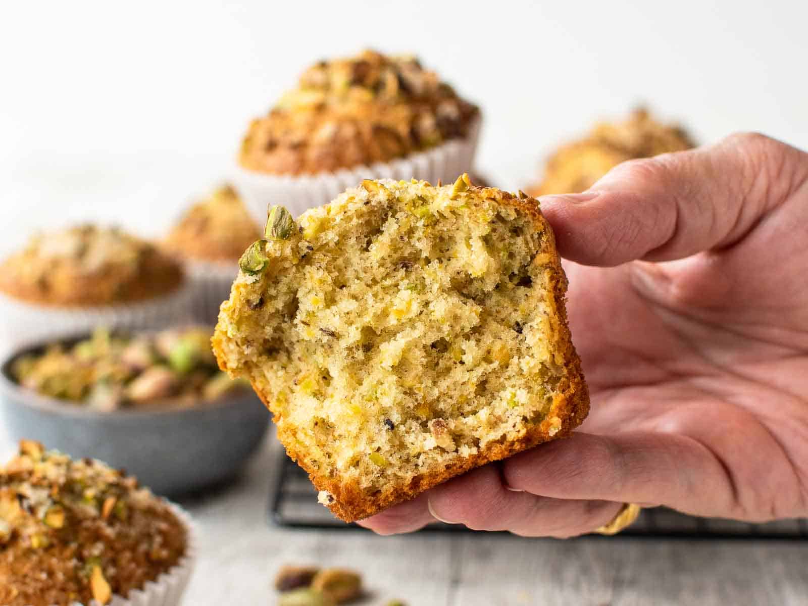 A close up view of a muffin split in half and being held by a female hand.