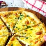 Garlic pizza cut in eight wedges. One slice being taken by hand.