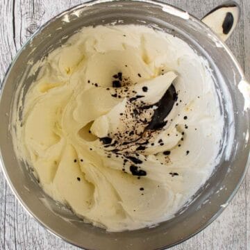 Off white, creamy mixture in the bottom of steel bowl with a little bit of brown liquid added.