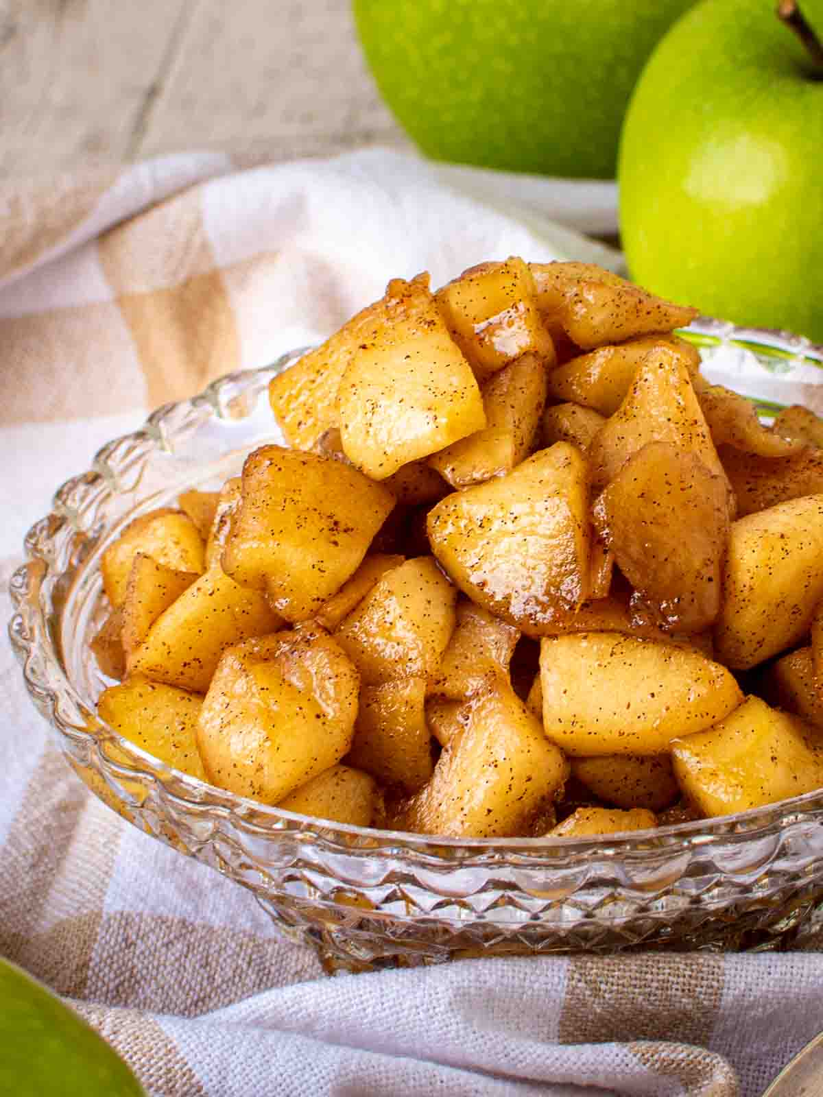 Apple compote in a cut glass dish with green apples in the background.