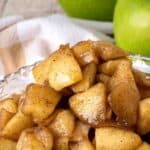 Apple compote in a cut glass dish with green apples in the background.