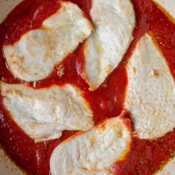 Lightly cooked chicken cutlets on tomato puree.