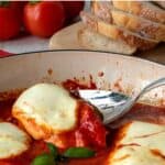 Chicken Pizzaiola in a red skillet with one piece being lifted out with a spoon.