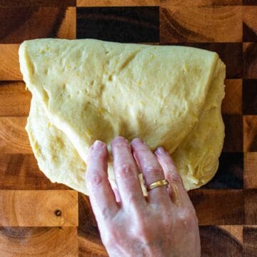 Pale yellow dough being folded in half.
