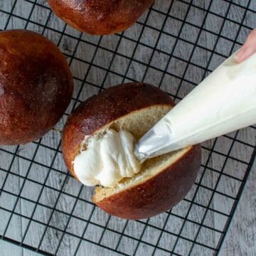 Piping cream into a split bun.