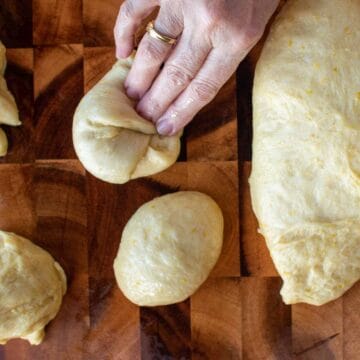 Balls of dough being shaped by hand.
