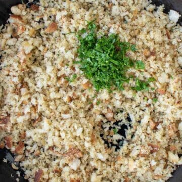 Green chopped herbs on top of bread crumbs.
