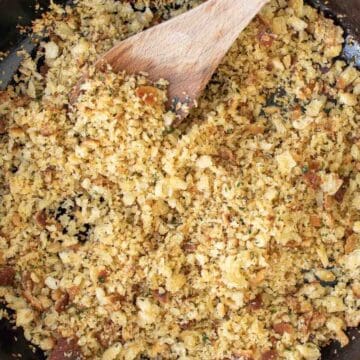 Golden brown bread crumbs with a wooden spoon scooping some up.
