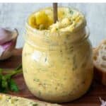 Roasted garlic butter in a jar with a spoon inserted.