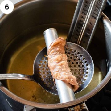 Fried cannoli shell being scooped out of oil.