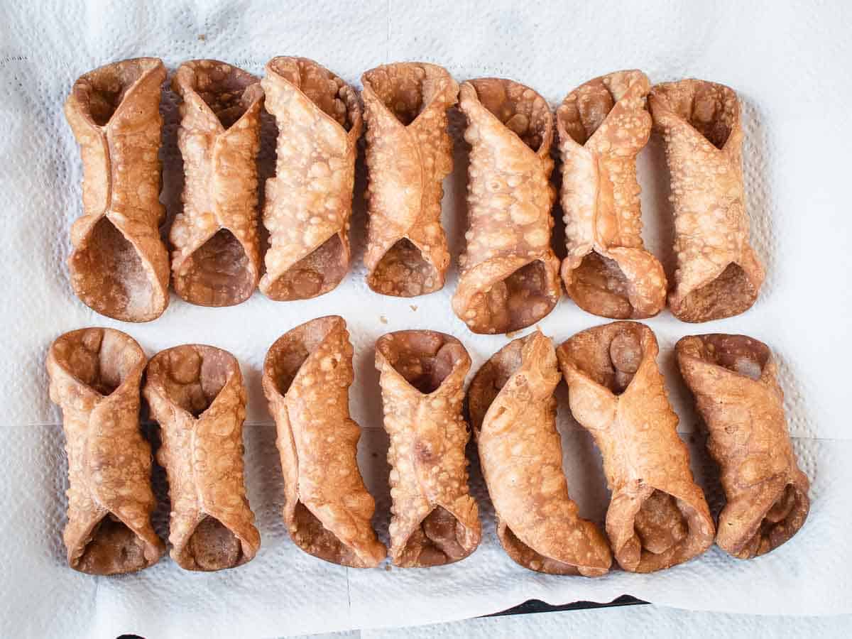 Overhead view of cannoli shells lined up on paper towels.