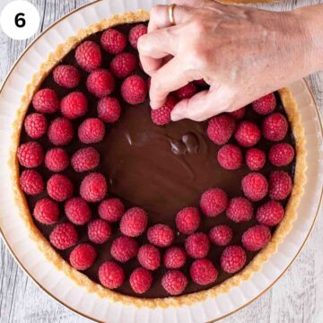Raspberried being arranged on a chocolate tart.