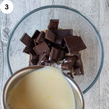 Chopped chocolate in a bowl with cream being poured over it.
